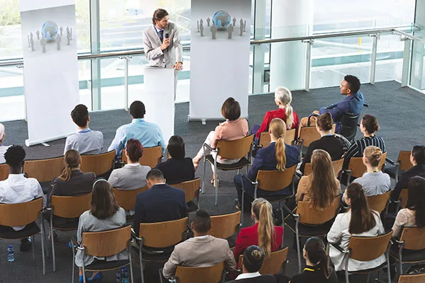 A man is speaking to a seated audience in front of him