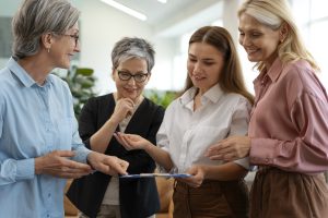 Women leading change in the social profit sector standing in a circle looking at something together